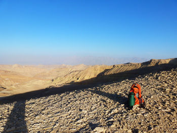 Rear view of man climbing on mountain against clear sky