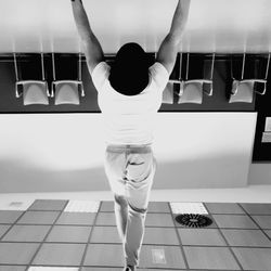 Rear view of woman standing on tiled floor