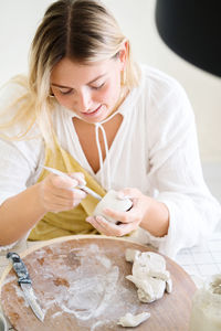 Female pottery artist making a vase in her home studio