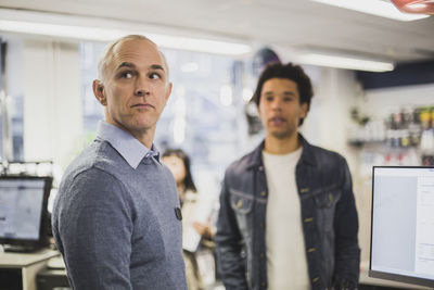 Male owner looking while customer standing in background at electronics store