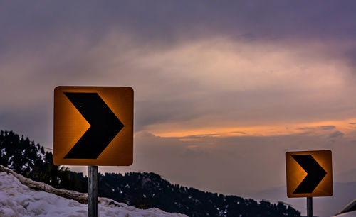 Road sign against sky during winter