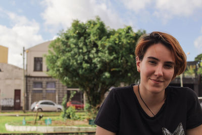 Portrait of young woman standing against trees