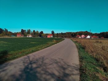 Empty road amidst field against clear sky