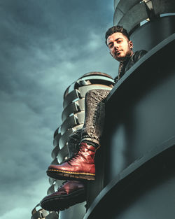 Low angle portrait of young man standing against sky