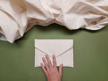 Cropped hand of woman holding envelope on table