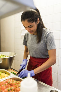 Smiling young chef chopping food in commercial kitchen at restaurant