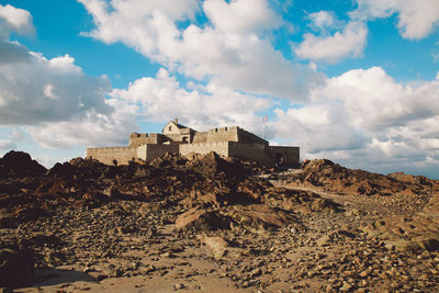 Low angle view of fort against cloudy sky