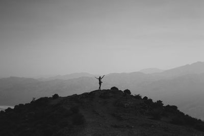 Man standing on rock against sky