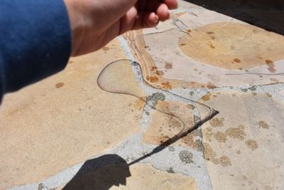 Cropped hand over shadow on footpath