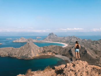 Full length of woman standing on mountain against blue sky