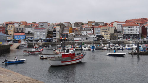 Boats moored in sea by buildings against sky