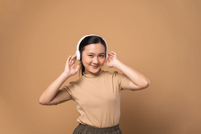 Portrait of young woman standing against yellow background