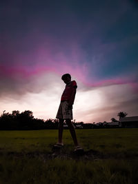 Man standing on field against sky during sunset