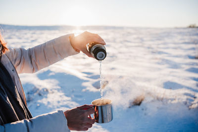 Midsection of woman making coffee outdoors during winter