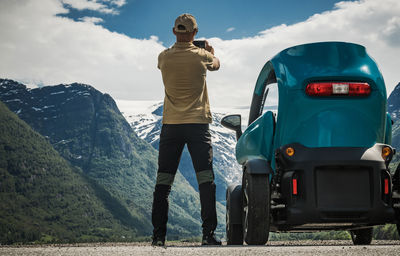 Rear view of man standing on mountain against sky