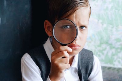 Close-up portrait of boy holding magnifying glass