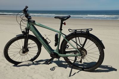 Bicycle on beach against sky