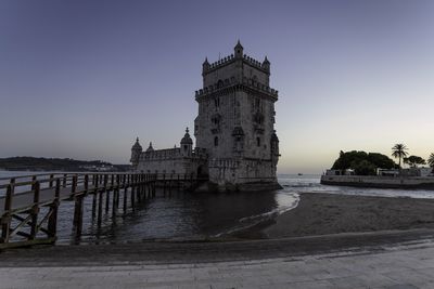 View of historic building by sea against clear sky