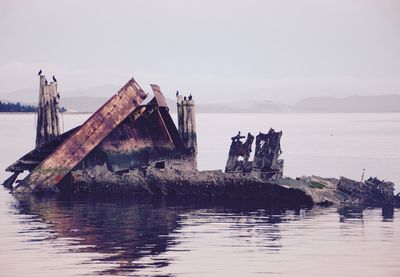 Abandoned ship in lake against sky