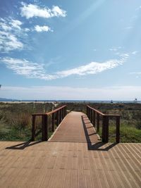 Empty footpath by sea against sky