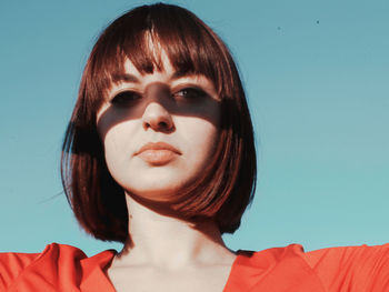 Portrait of beautiful young woman against clear blue sky