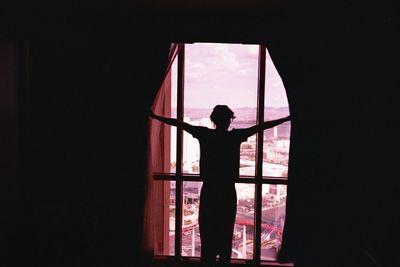 Rear view of silhouette woman standing against window