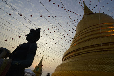 Buddha statue at temple against sky during sunset