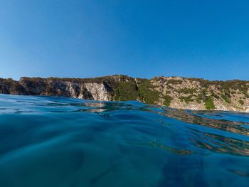 Surface level of sea against clear blue sky