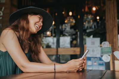 Portrait of young woman using mobile phone at table