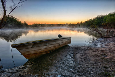 Boat moored on lake against sky