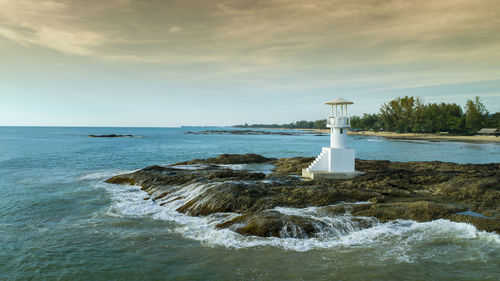 Lighthouse by sea against sky