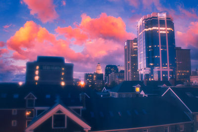 Illuminated buildings against cloudy sky at dusk