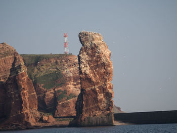 Rock formations by sea against clear sky