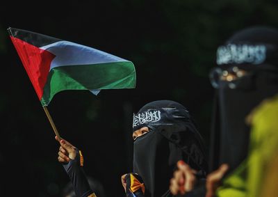 Woman in burka holding flag outdoors