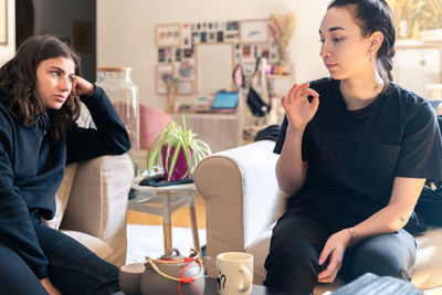 Women having discussion while sitting on sofa at home