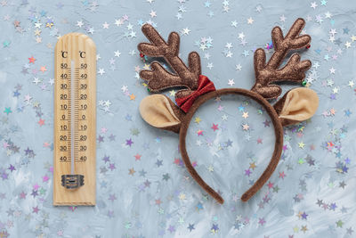 Thermometer shows low temperature and christmas deer headband costume on blue and white
