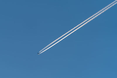 Low angle view of airplane flying against clear blue sky