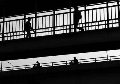 Silhouette people walking on bridge