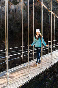 Front view of woman crossing a suspension bridge