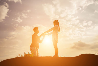 Silhouette friends standing against sky during sunset