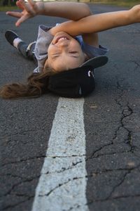 Portrait of young woman lying on road