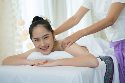 Smiling young woman receiving massage in spa
