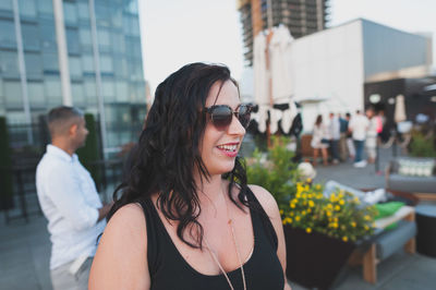 Smiling young woman wearing sunglasses while looking away in city