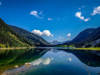 Scenic view of lake and mountains against blue sky