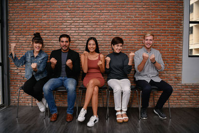 Portrait of smiling colleagues clenching fists in office