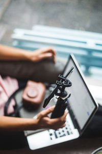 High angle view of young female influencer using mobile phone on tripod for vlogging at creative office