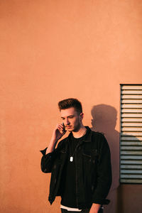 Young man looking away against wall