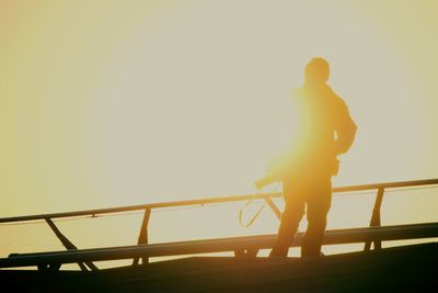 People on railing at sunset