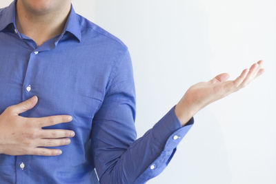 Midsection of man gesturing while standing against white background