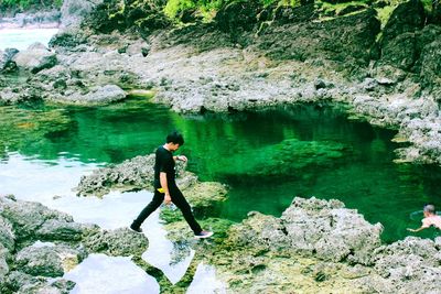 Side view of woman standing on rock by lake